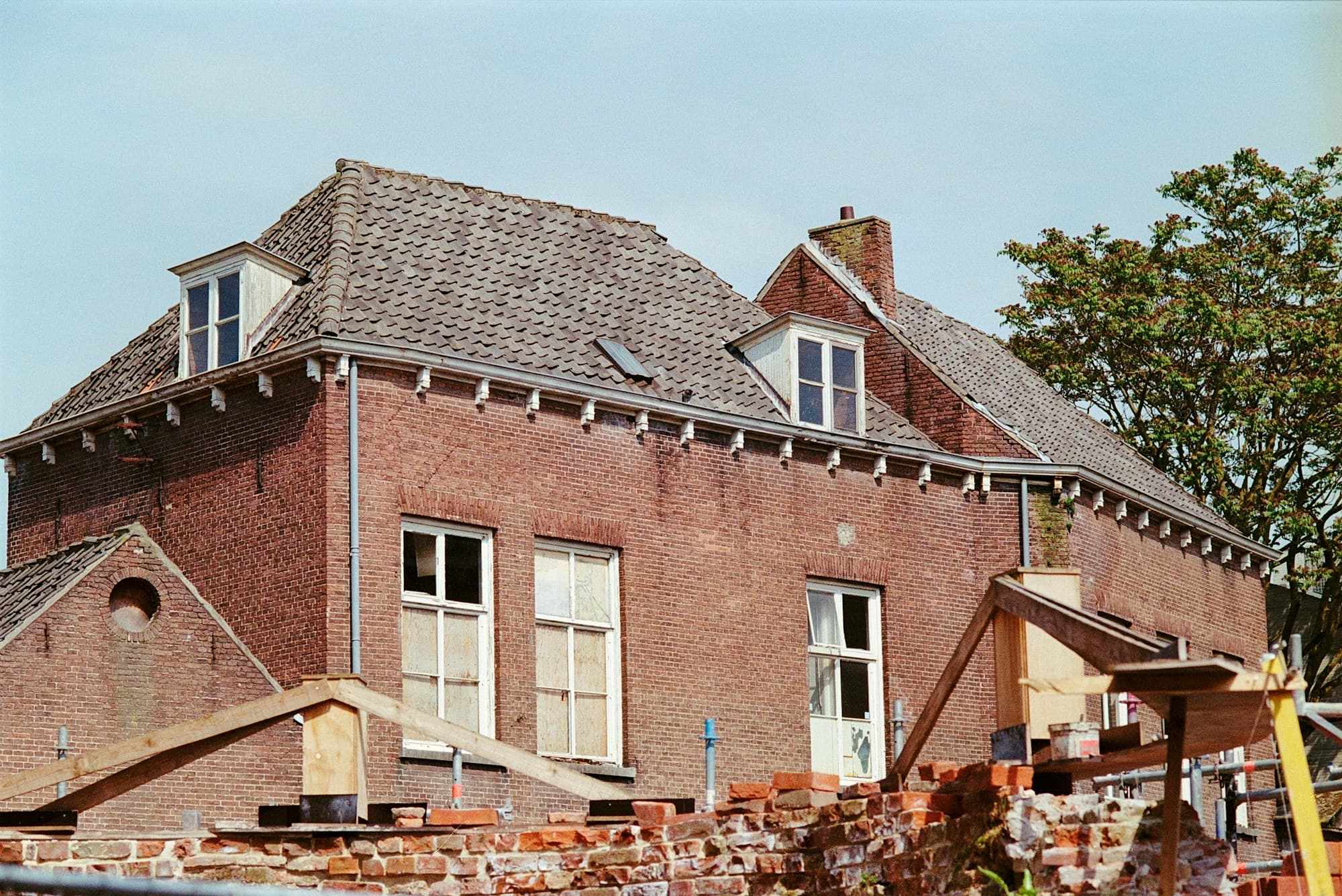 Bakstenen woning met dakkapellen en een schuin dak, met bakstenen en bouwmateriaal op de voorgrond